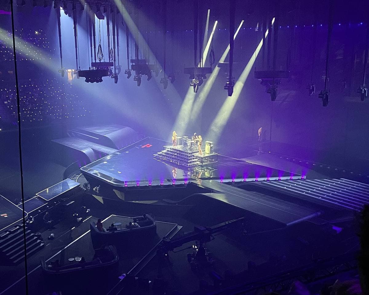 A purple-lit arena stage seen from high up, the band on a raised platform