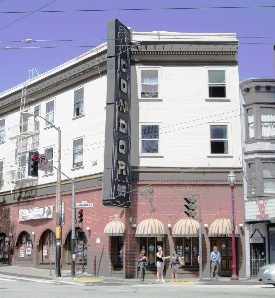 A corner building at Broadway and Columbus with a tall vertical club sign
