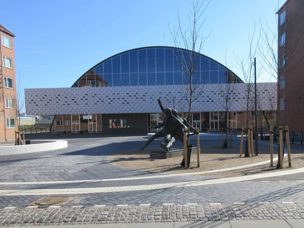 A long low arena with a curved roof and a glass front on a clear day