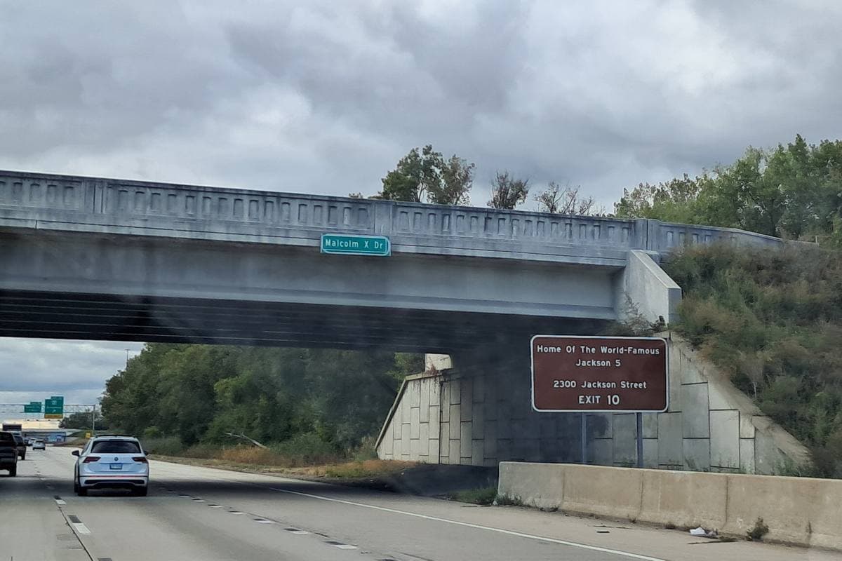 A brown highway sign beside an overpass reading Home of the world-famous Jackson 5, 2300 Jackson Street