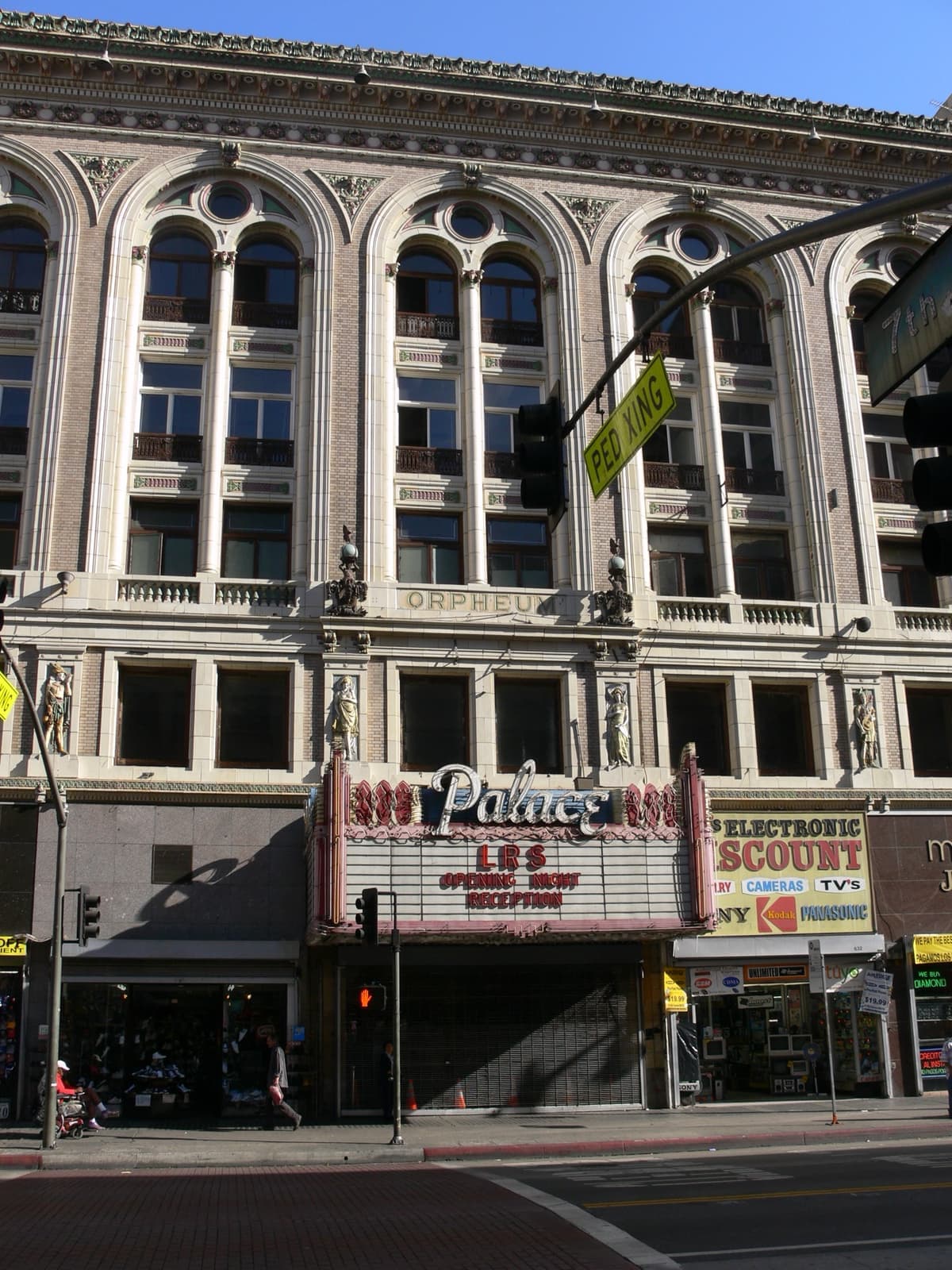 A cream terracotta theatre front with arched upper windows and a marquee over the pavement