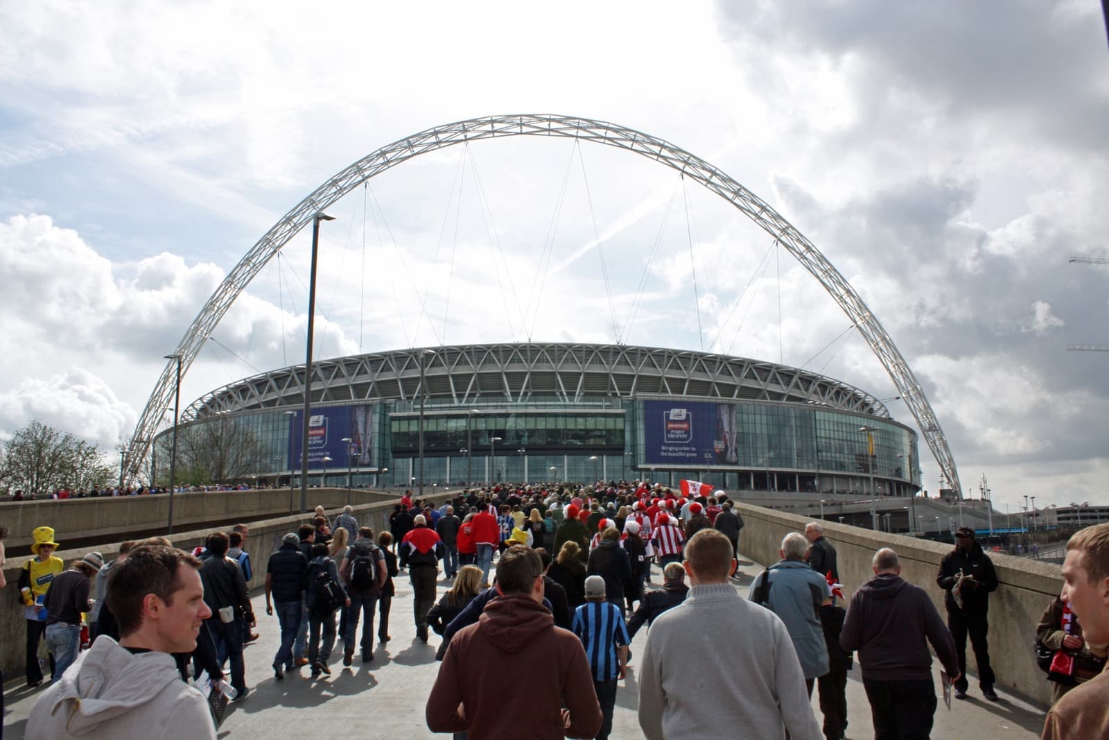 Crowds walking towards Wembley Stadium under its white arch