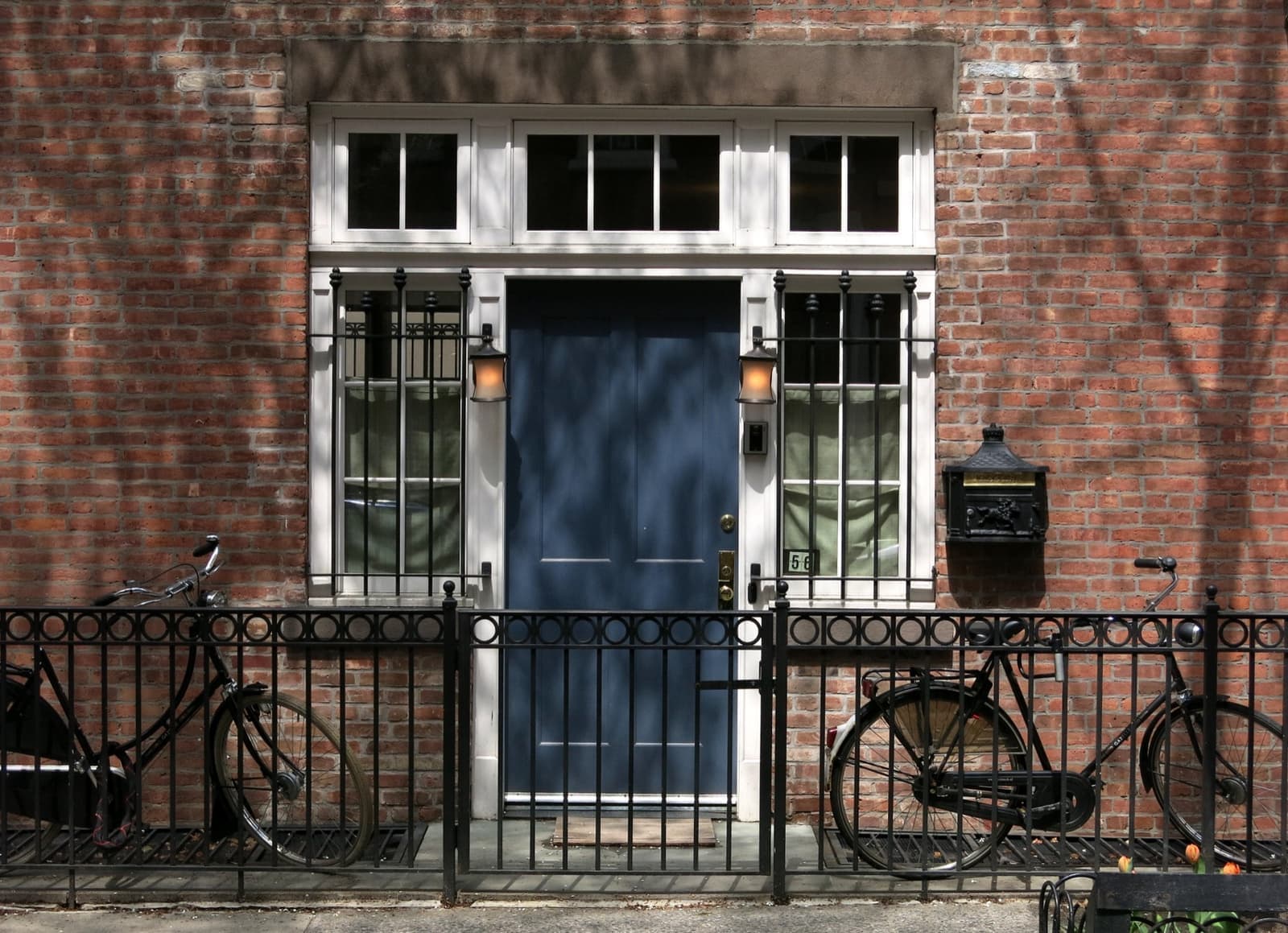 A brick front on Barrow Street with a blue door, iron railings and two bicycles