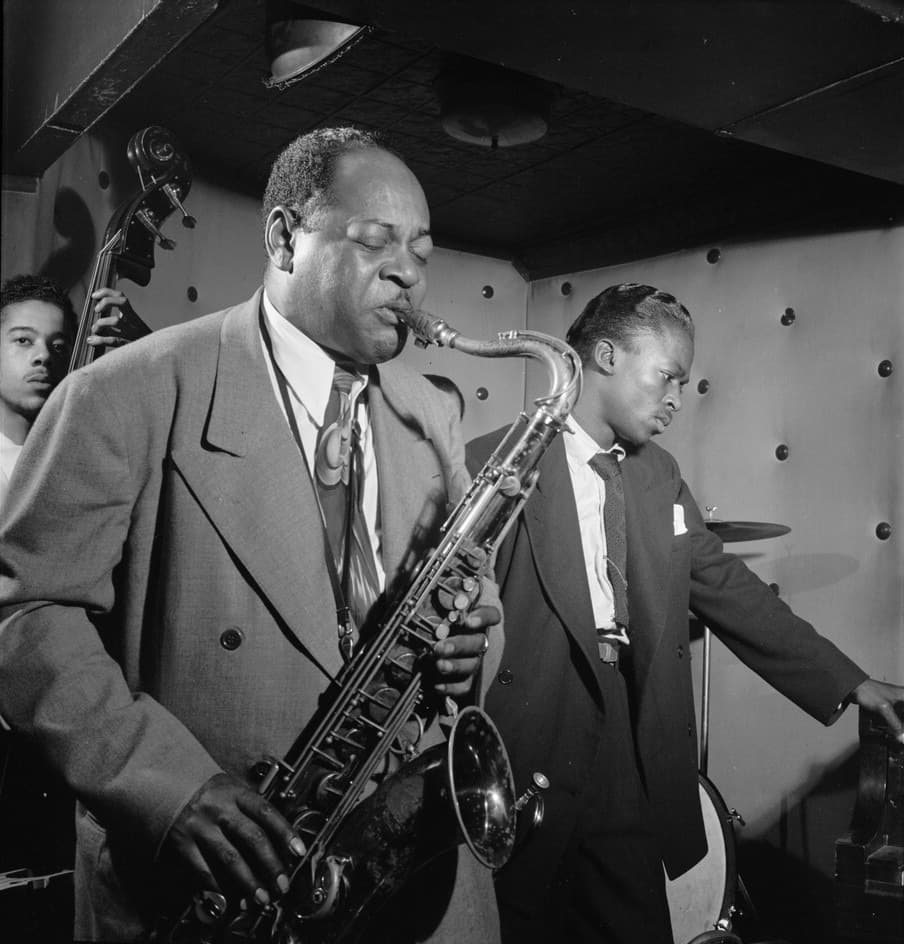 Coleman Hawkins and a young Miles Davis side by side in a club