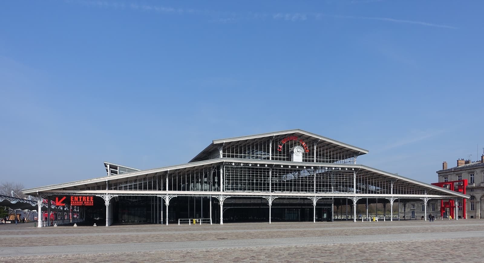 A long nineteenth-century iron and glass market hall across an open paved square