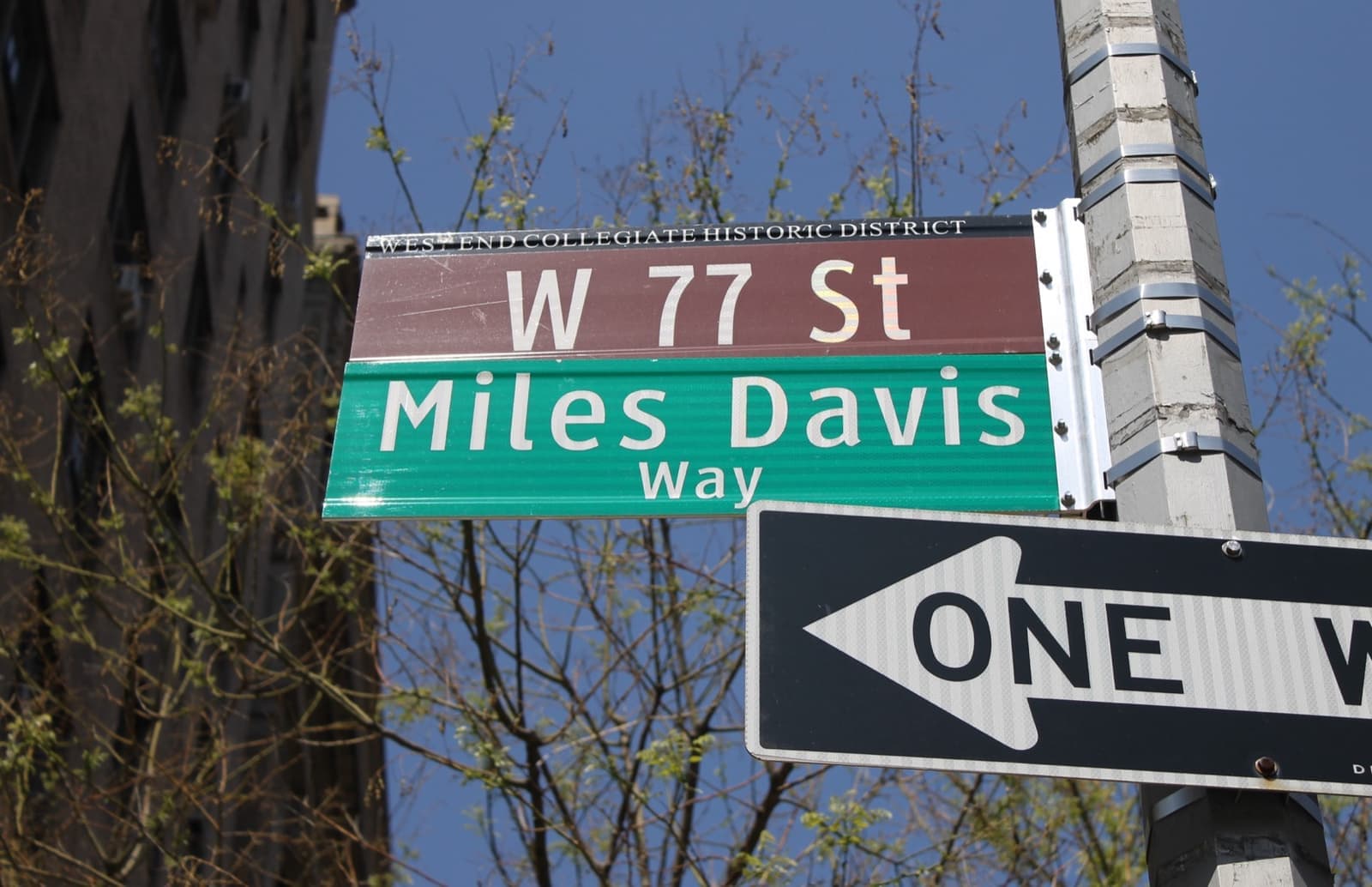 A green Miles Davis Way sign beneath a brown W 77 St sign and a one-way arrow