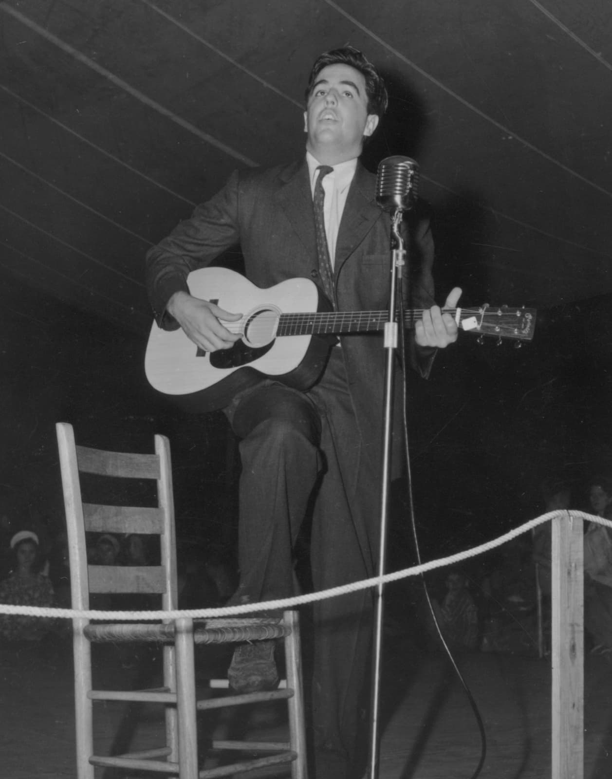 A young Alan Lomax playing guitar on a stage