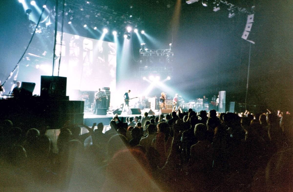 Oasis on a white-lit stage seen over a dark crowd