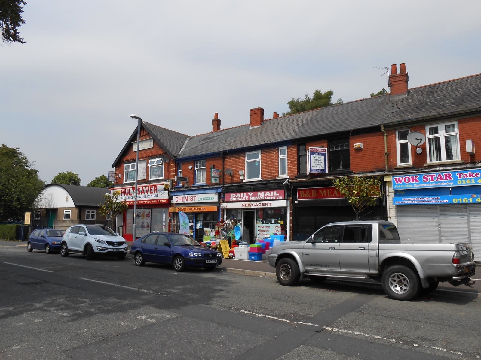 A row of shops on a wet street, the Sifters sign on the right beside a set of traffic lights