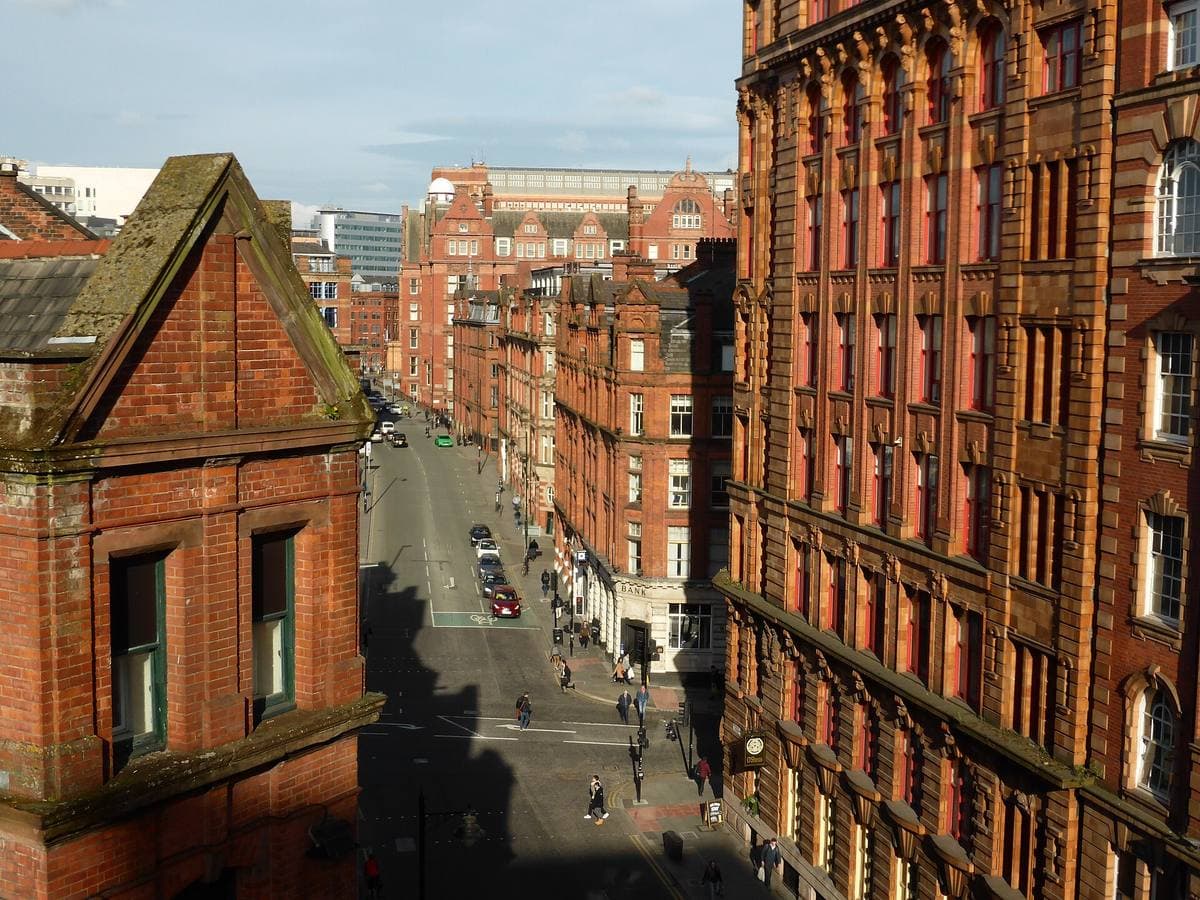 Looking down Whitworth Street between tall red-brick warehouse blocks