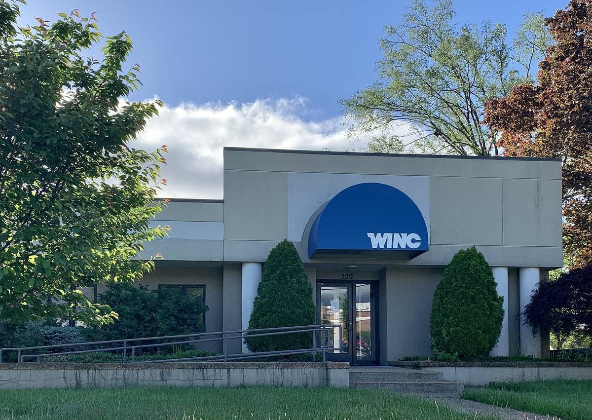 A low modern office building with a blue WINC awning
