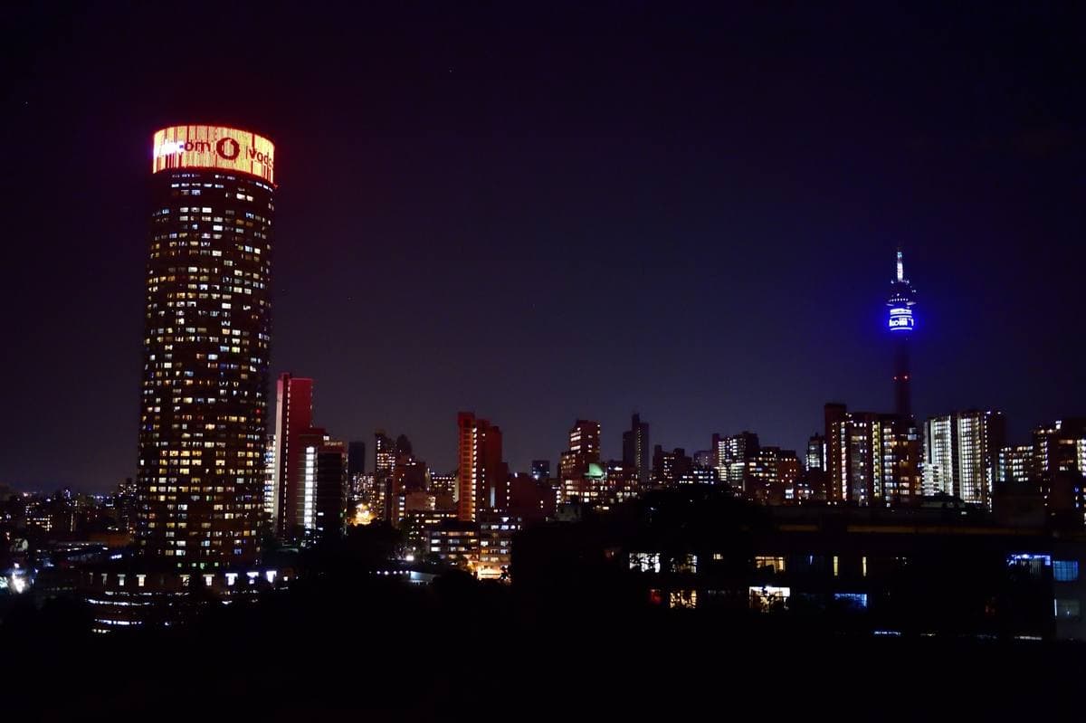 The Johannesburg skyline at night with a lit cylindrical tower