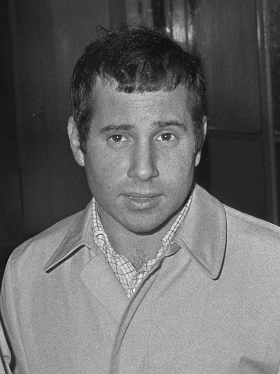Black-and-white portrait of a young Paul Simon in a light jacket