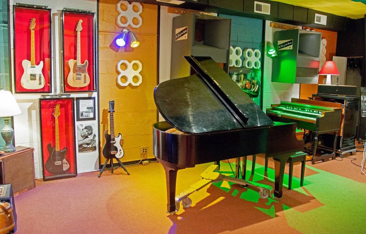 A studio room with a grand piano, an organ and guitars on the walls