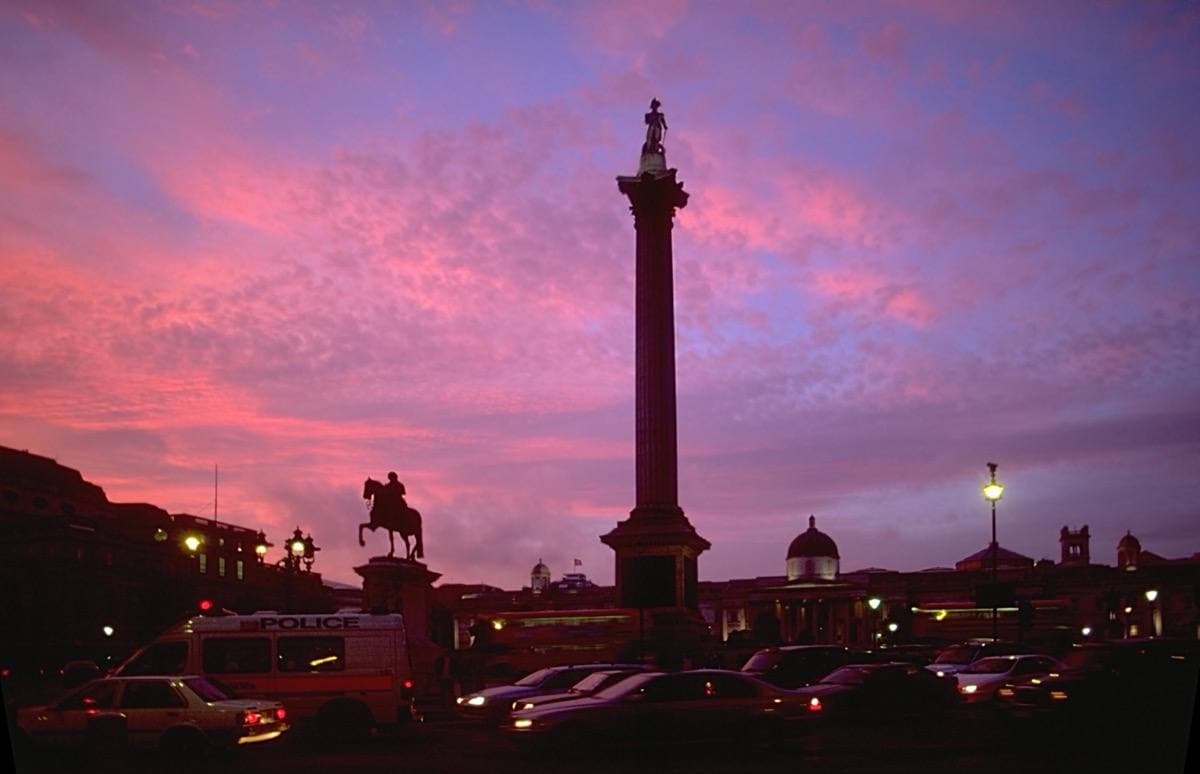 Nelson's Column silhouetted against a pink and violet evening sky over Trafalgar Square
