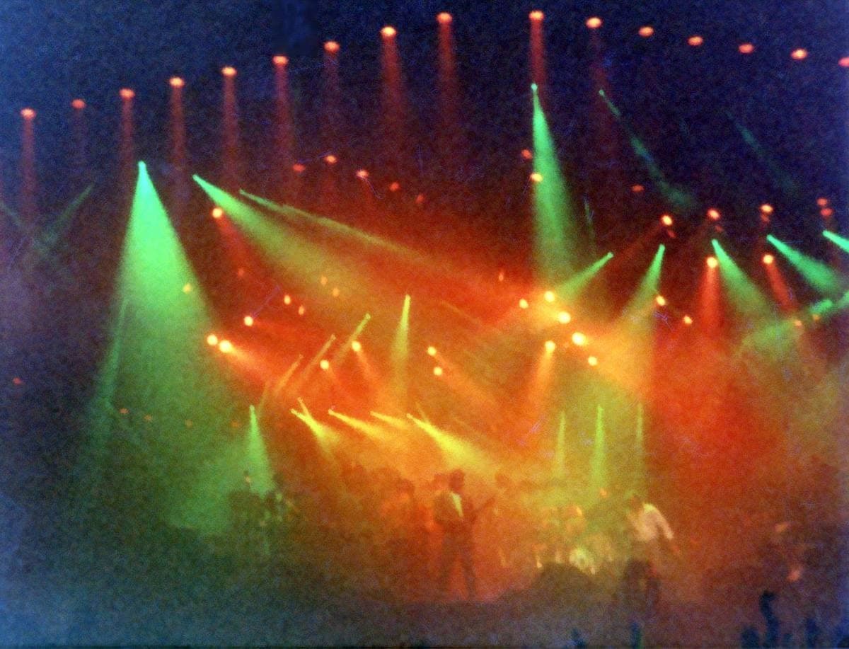 Beams of green, orange and red light over a stage at night