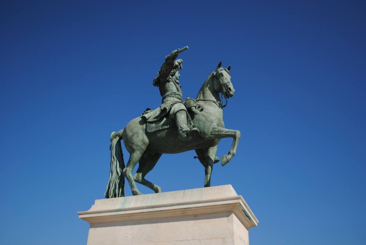 A bronze equestrian statue against a deep blue sky