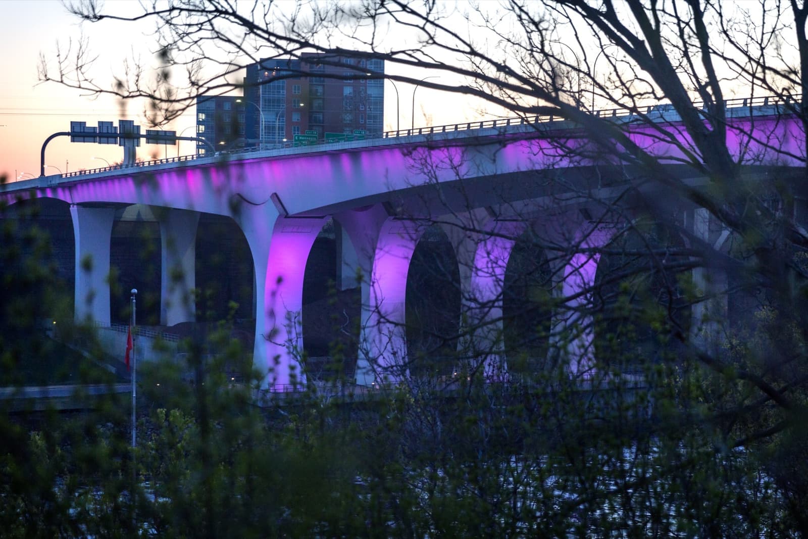 A long bridge over a river glowing purple at night