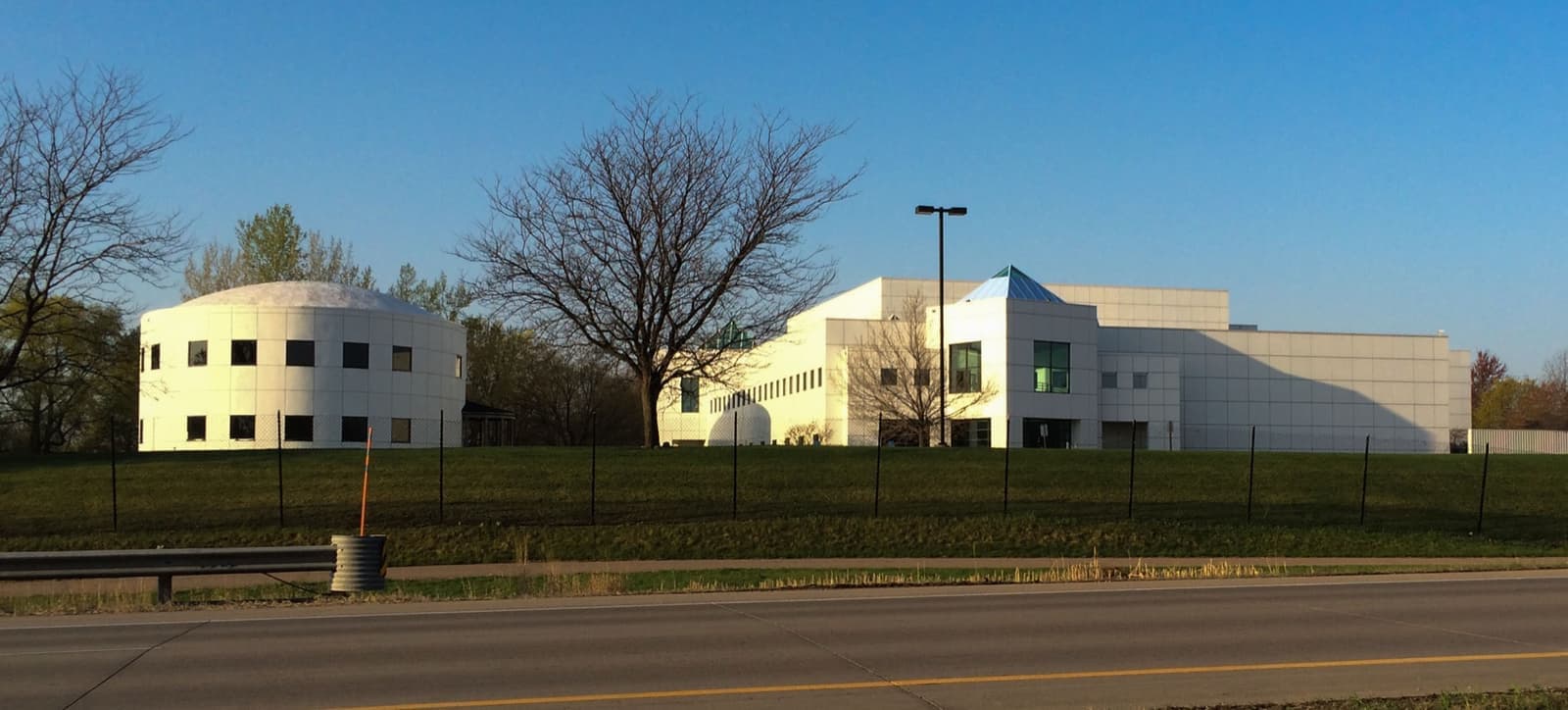 Low white buildings of Paisley Park behind a fence beside a highway