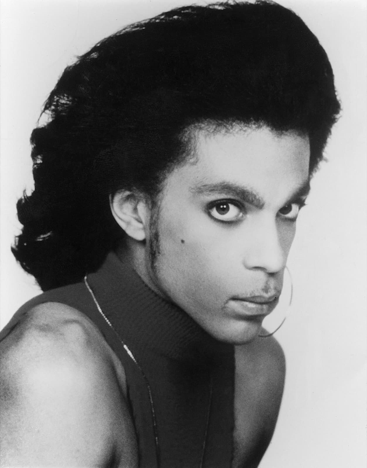A black-and-white portrait of Prince with a hooped earring