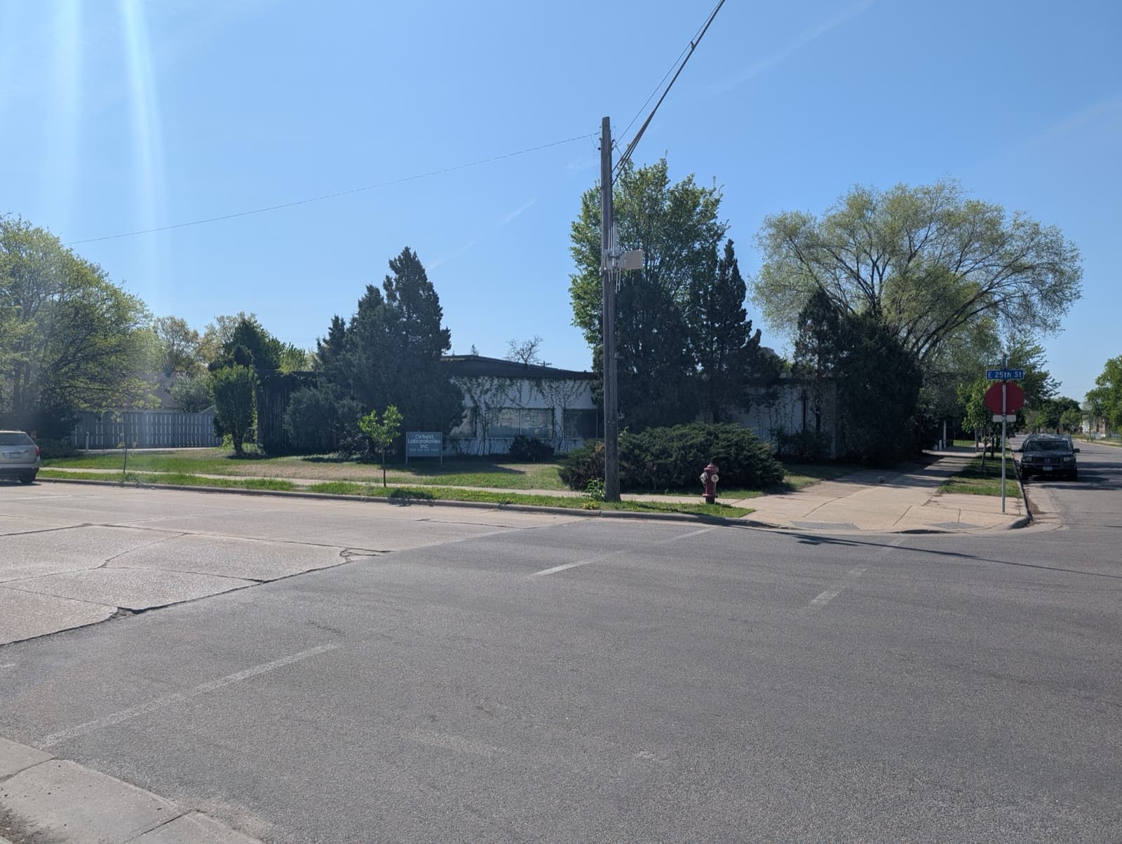A low building behind trees on a wide street corner