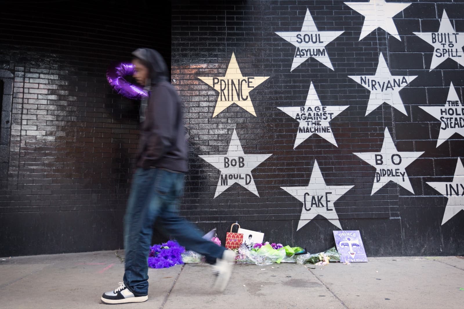 A gold star reading PRINCE among white stars on a black brick wall
