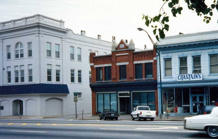A row of two- and three-storey shop fronts on a sunny street corner