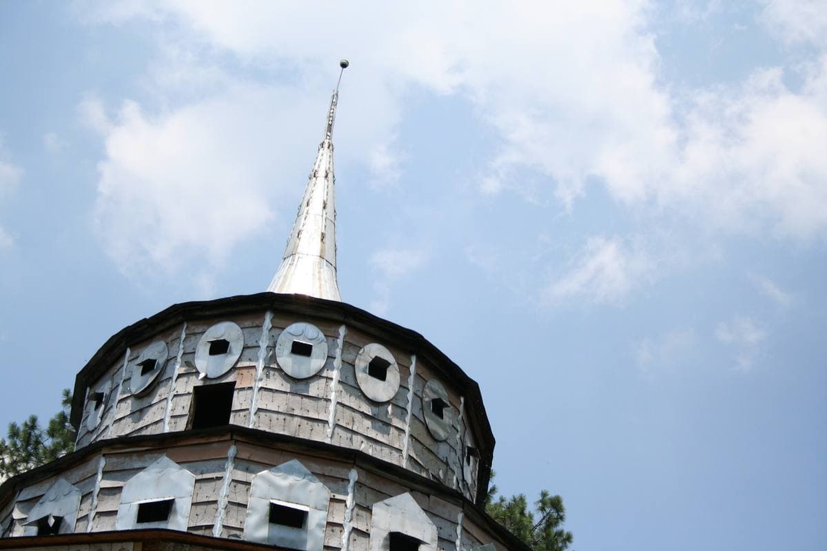 A round tiered white building with a tall spire against a blue sky