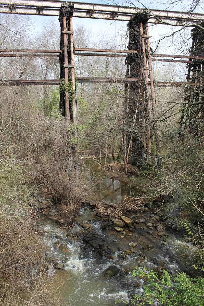 Timber trestle legs rising over a rocky creek and bare winter scrub