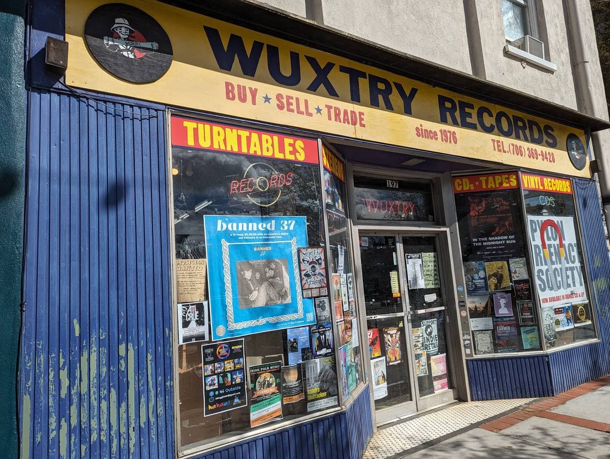A record shop front with a yellow sign reading Wuxtry Records and posters in the windows