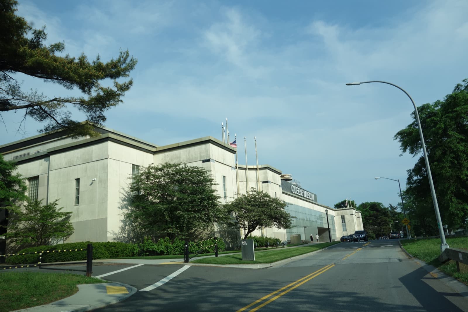 A long pale museum building behind trees and a curving road