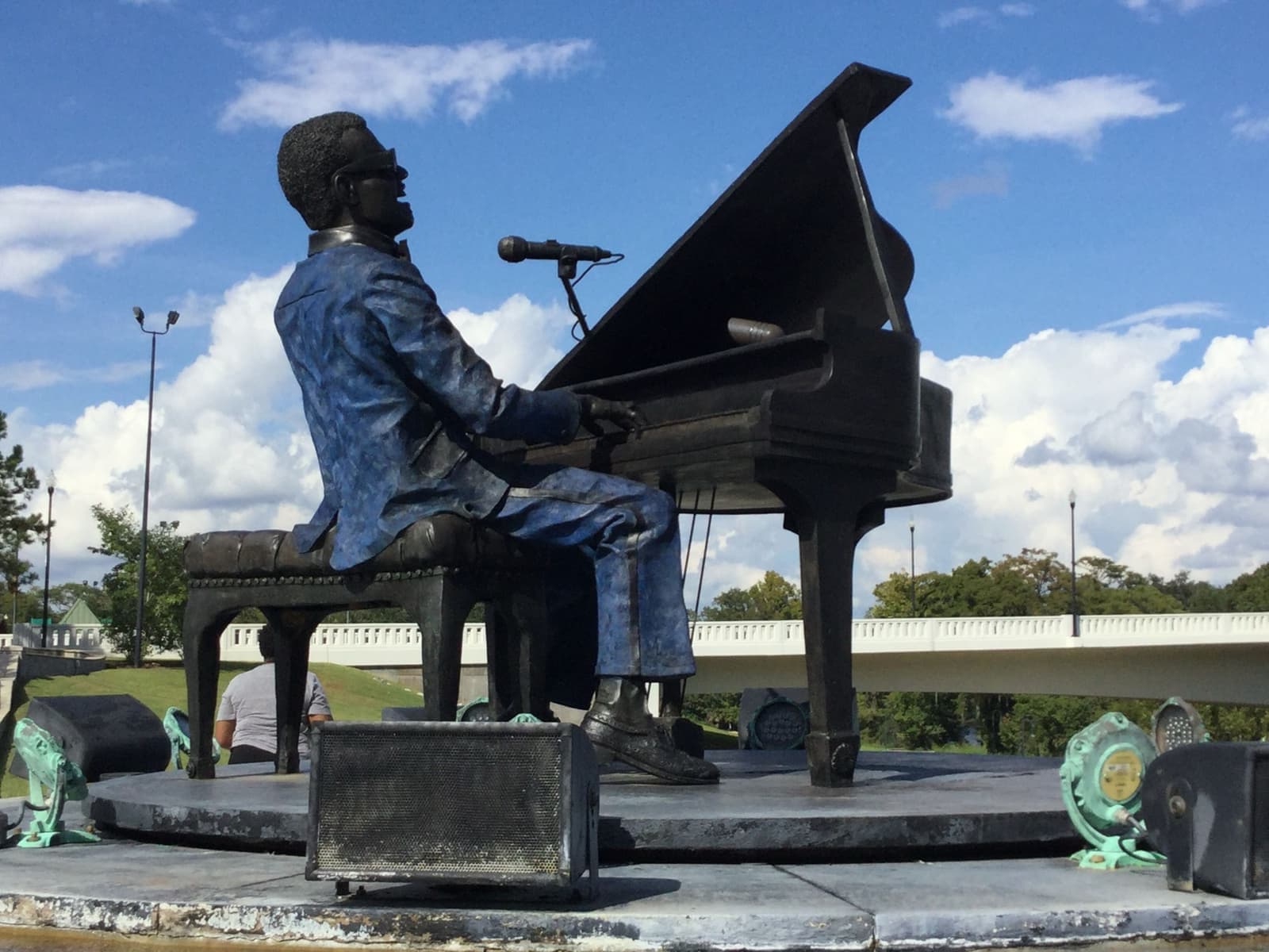 Bronze statue of Ray Charles playing a grand piano with a microphone, on a round base by the river