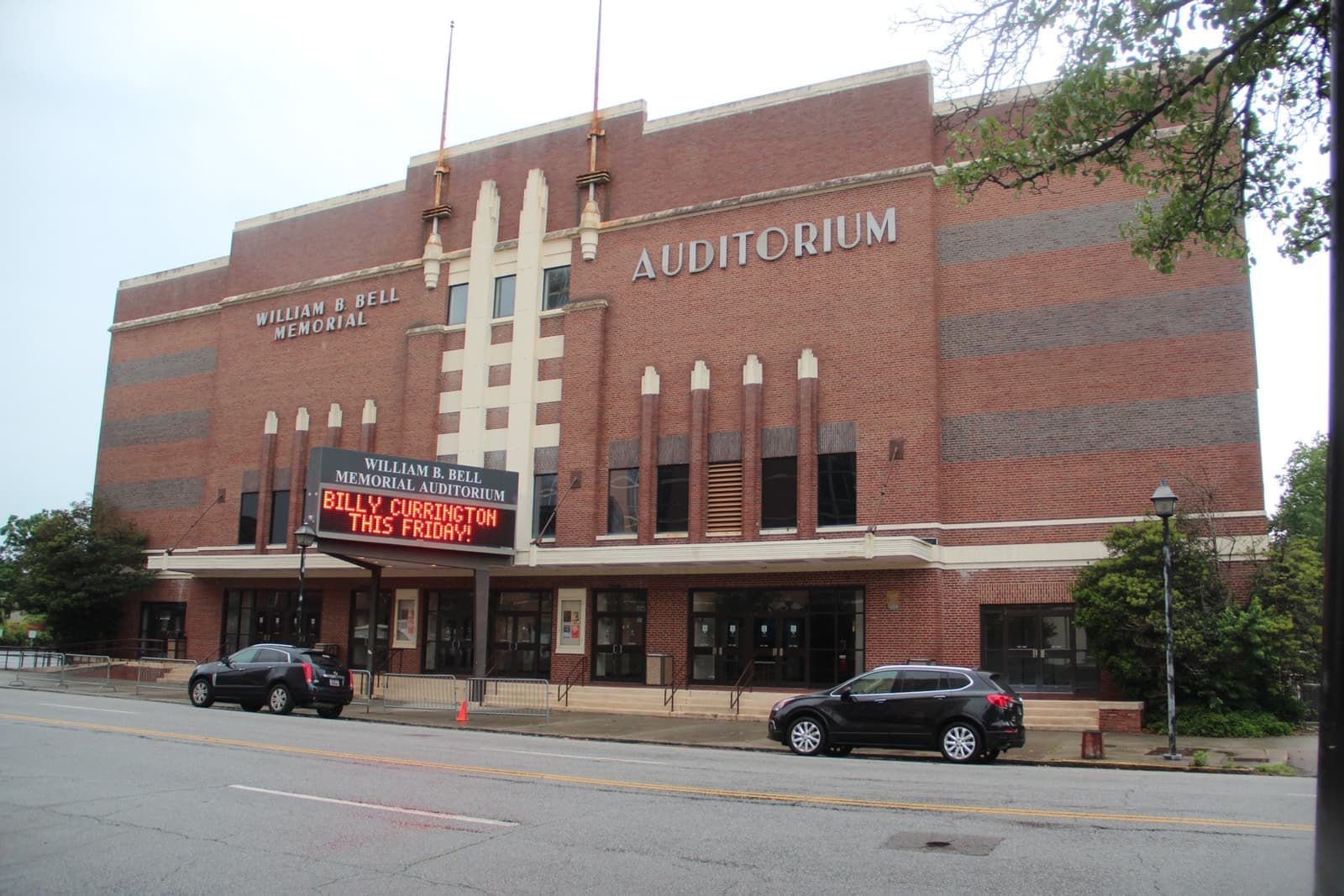 A tall red-brick Art Deco auditorium with a lit marquee on a street corner