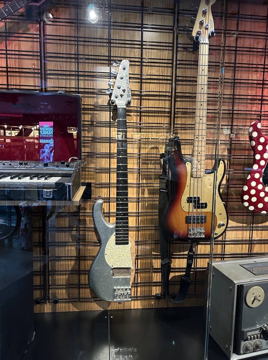 A silver sparkle bass guitar in a museum case