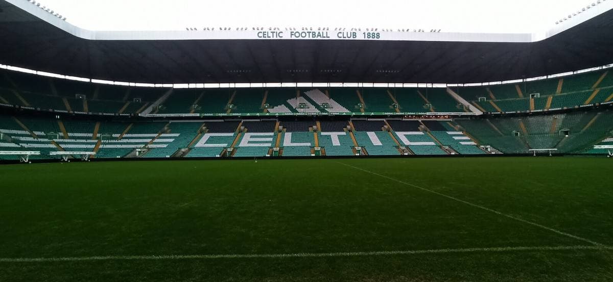 A green football pitch surrounded by tall green-and-white stands