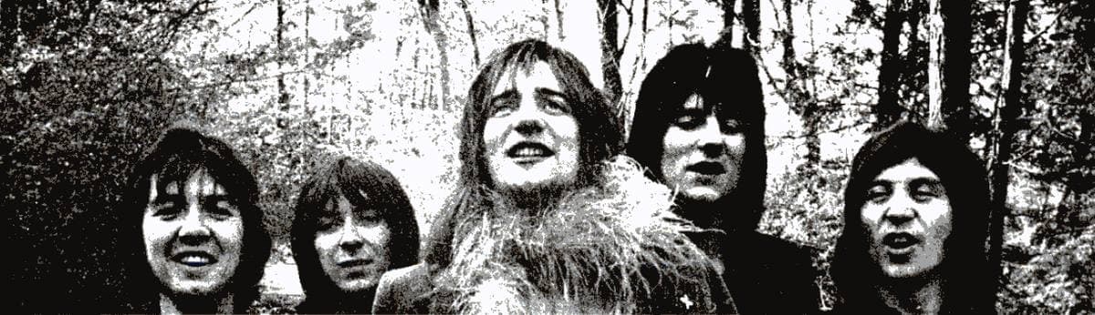 Five young men with long hair in a black-and-white row among trees