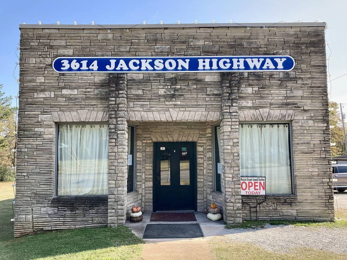 A low stone-faced studio building with a blue sign reading 3614 Jackson Highway
