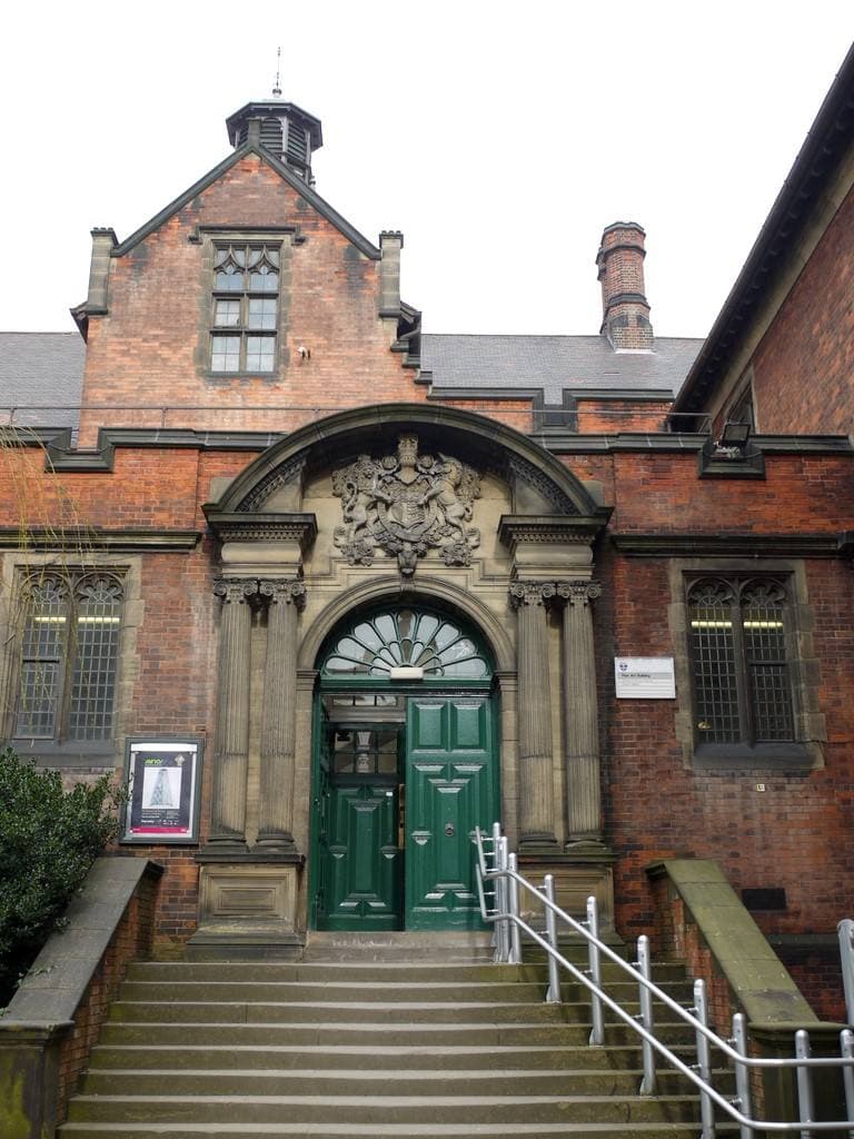 A red-brick building entrance with a carved stone doorway and steps
