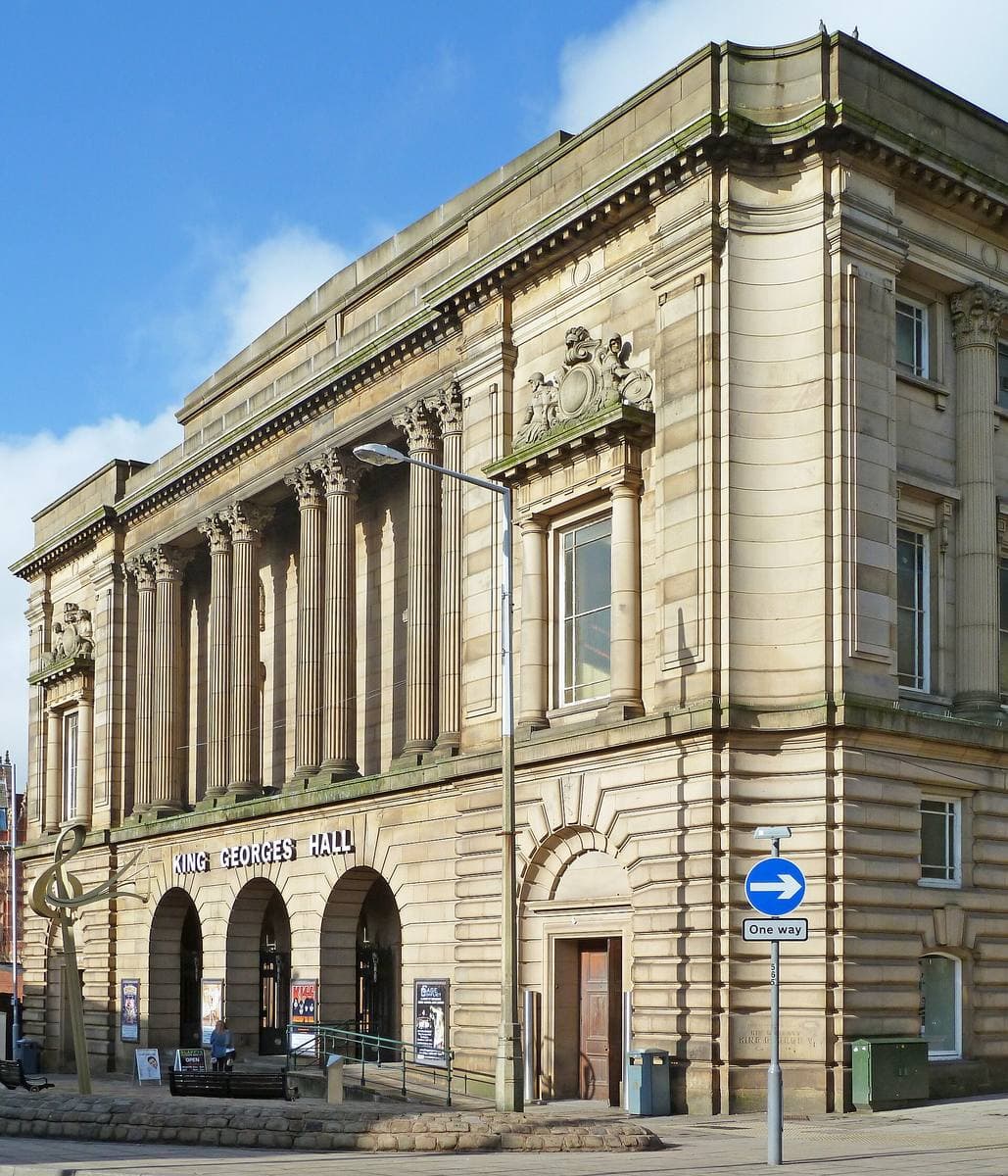 A pale stone civic hall with tall columns on a street corner
