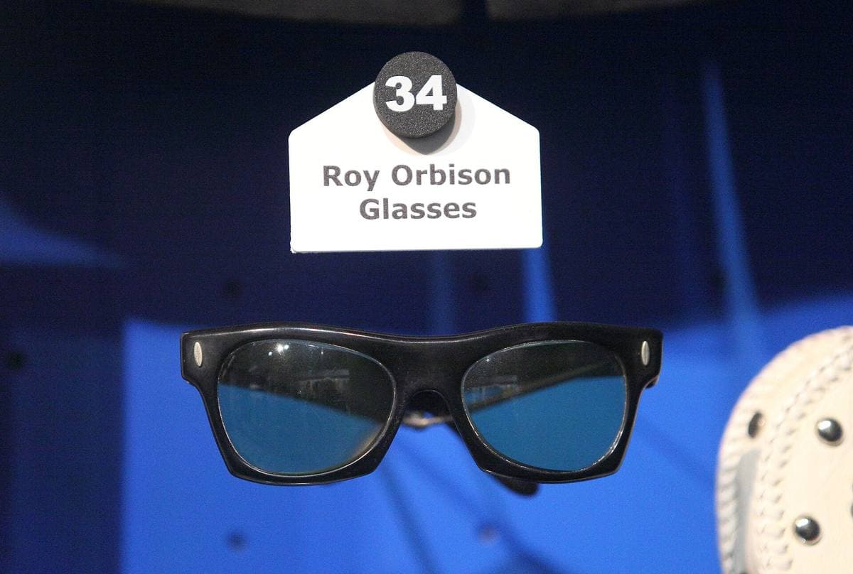 A pair of black sunglasses in a museum display case