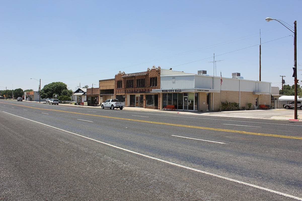 A wide, empty main road through a small West Texas town
