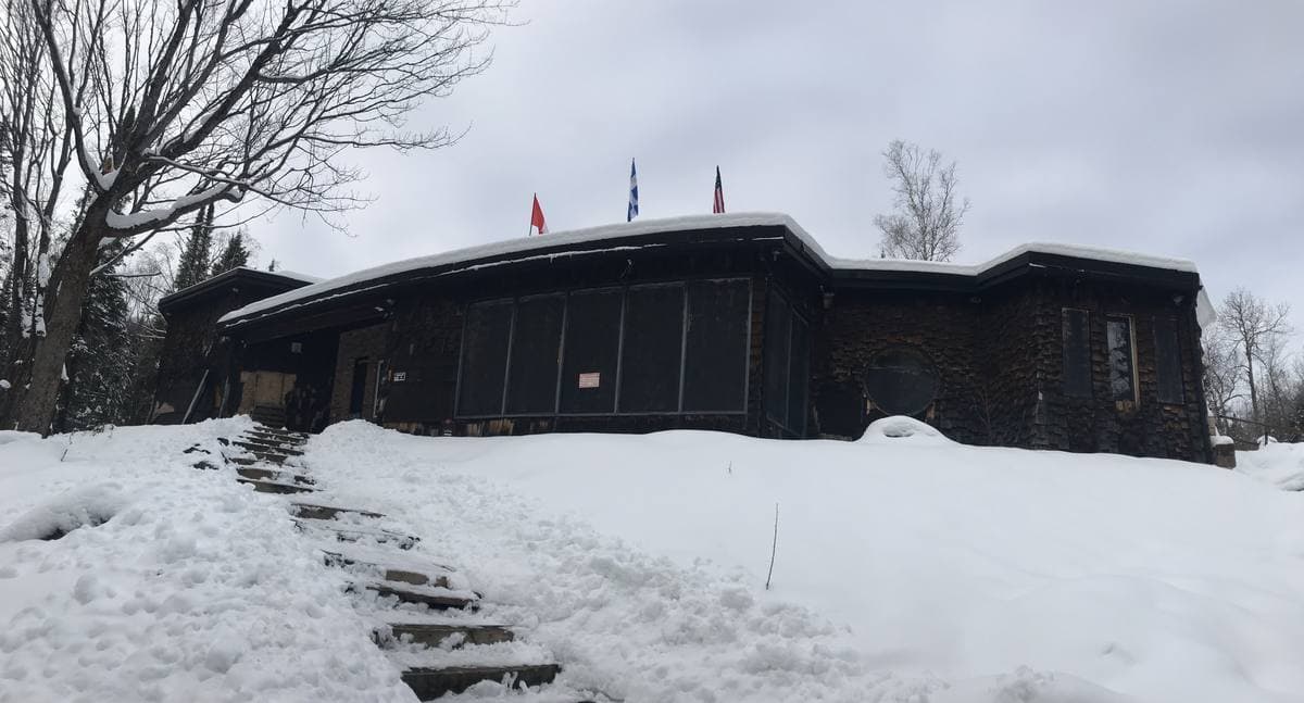 A burned-out wooden building among trees in winter