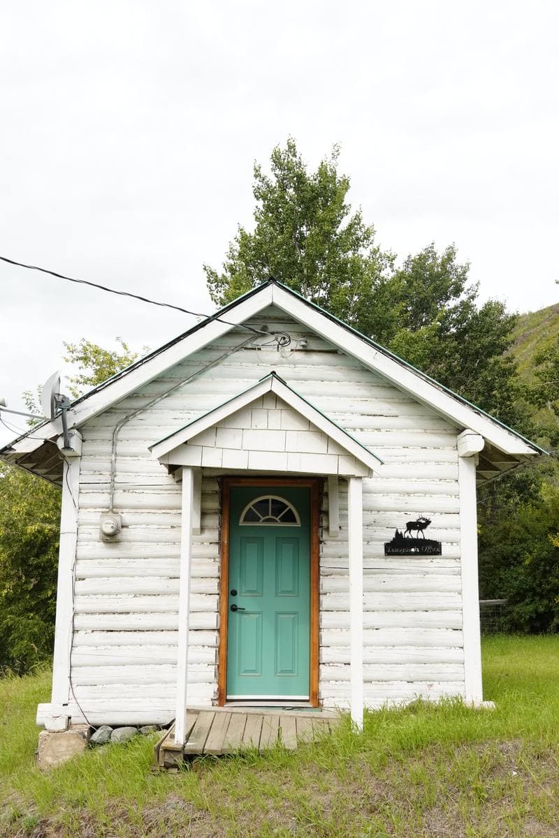 A weathered two-storey wooden building on a gravel street in a small northern village