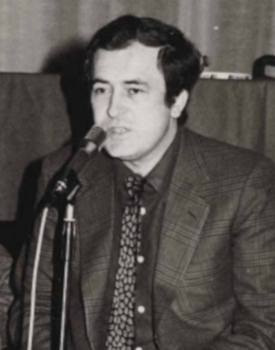 Bernardo Bertolucci speaking into a microphone, black and white