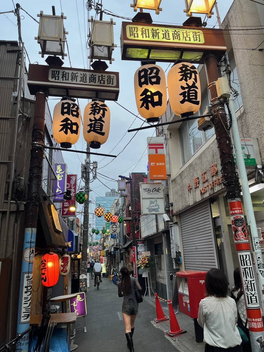 A narrow street lined with shop signs and paper lanterns
