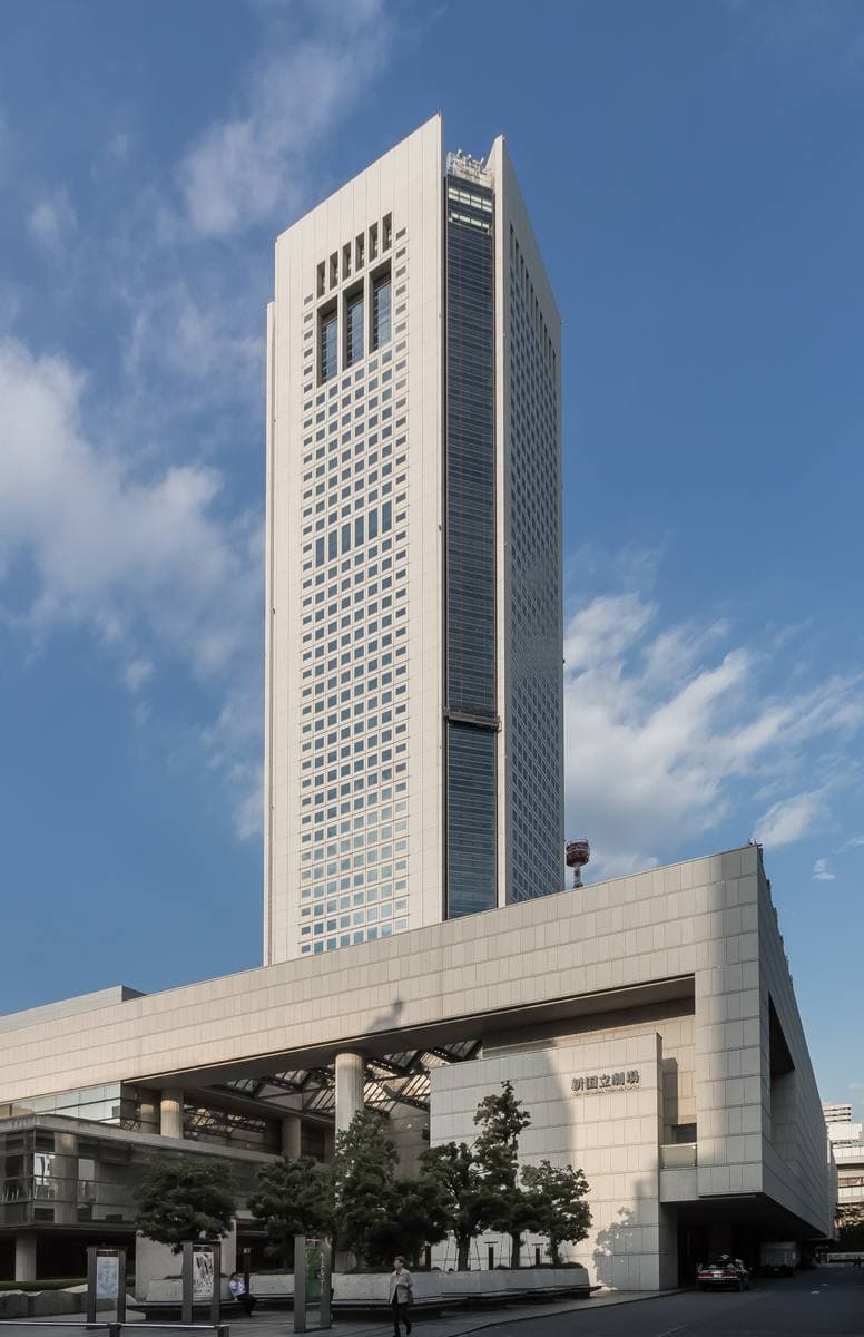 A tall office tower rising above a low cultural complex