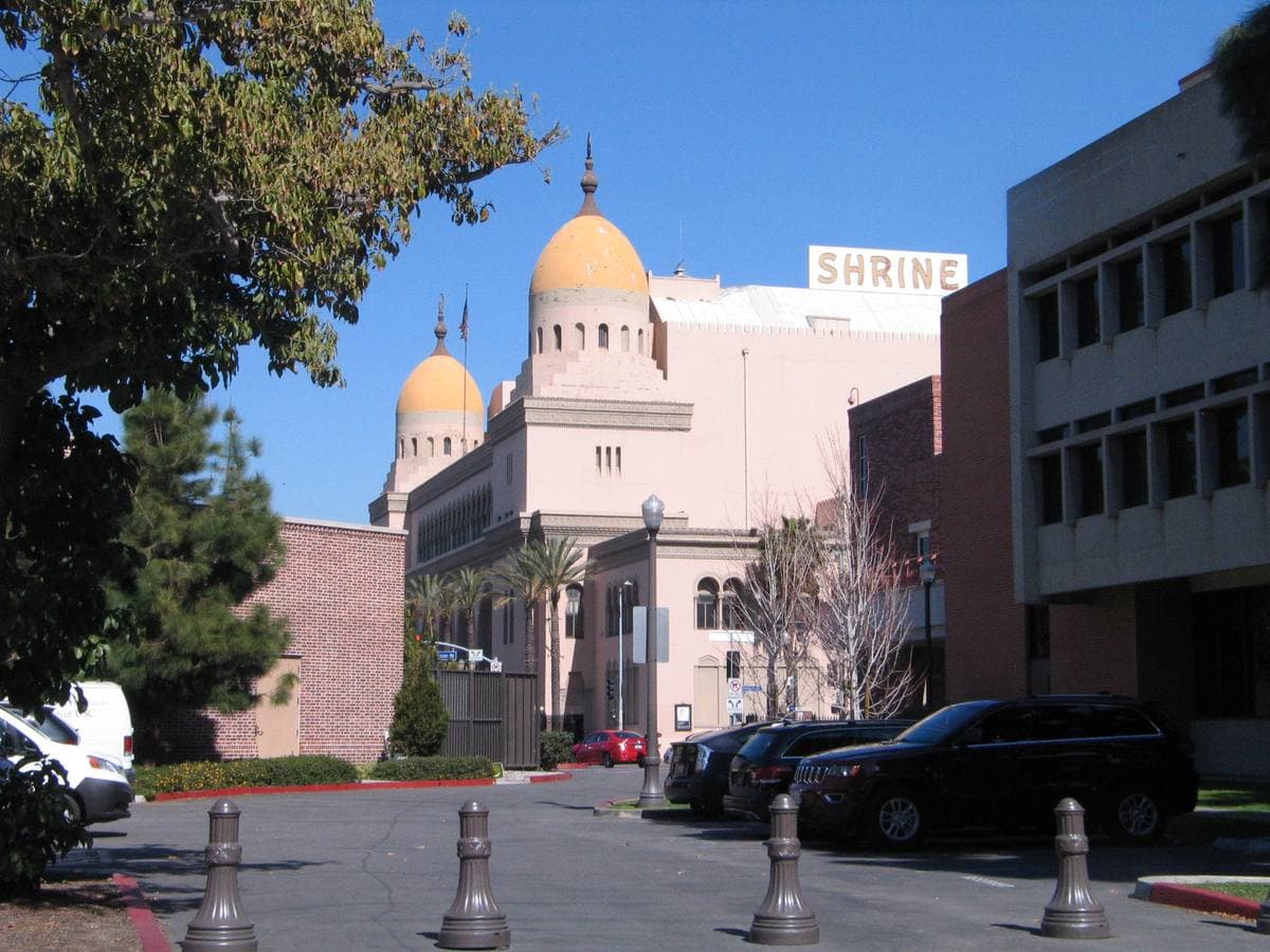A Moorish-style auditorium with domes and arches against a blue sky