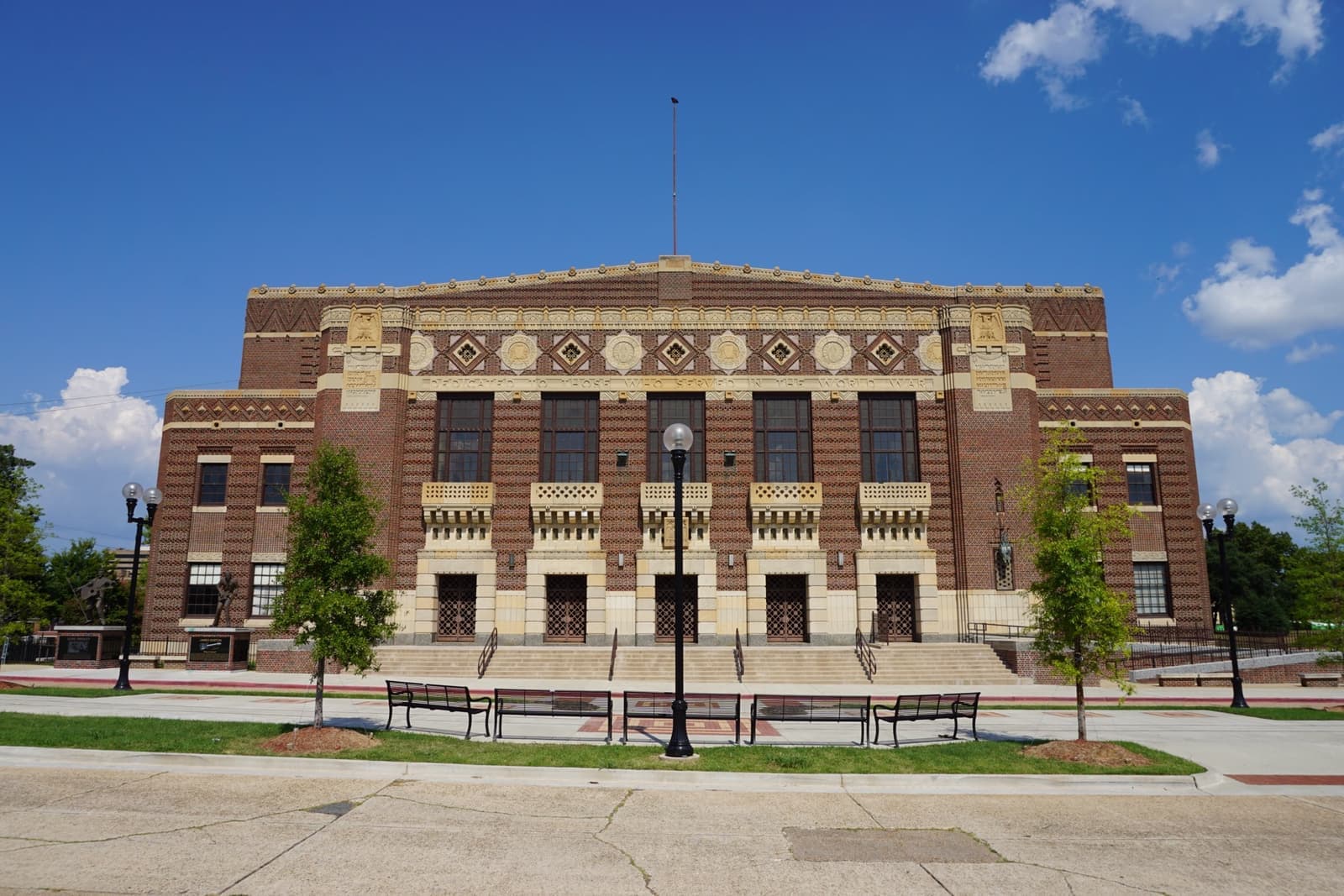 A long brick Art Deco auditorium with patterned stonework under a blue sky