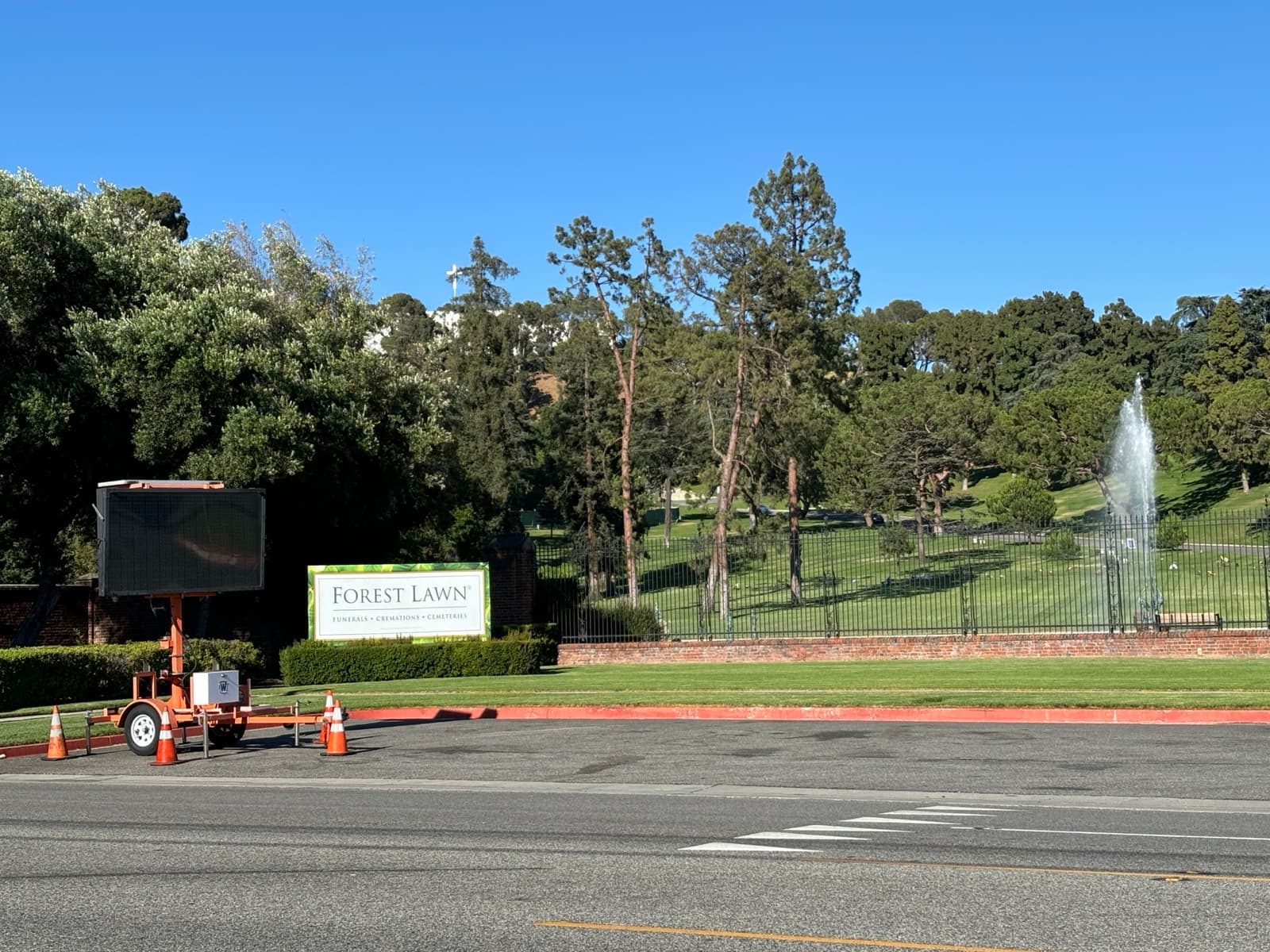 Green lawns, a fountain and trees behind the Forest Lawn sign in Glendale