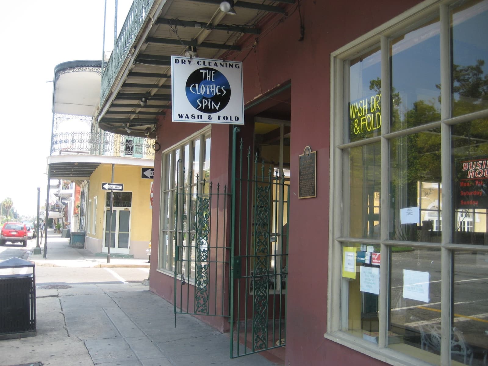 A shopfront on North Rampart Street, New Orleans, with iron gates, a hanging sign and a historic plaque